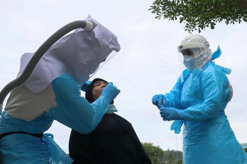 Medical officers in personal protective equipment conduct a Covid-19 coronavirus test on a woman in southern Thailand's Yala province, amid an increase in active case numbers in the region. AFP
