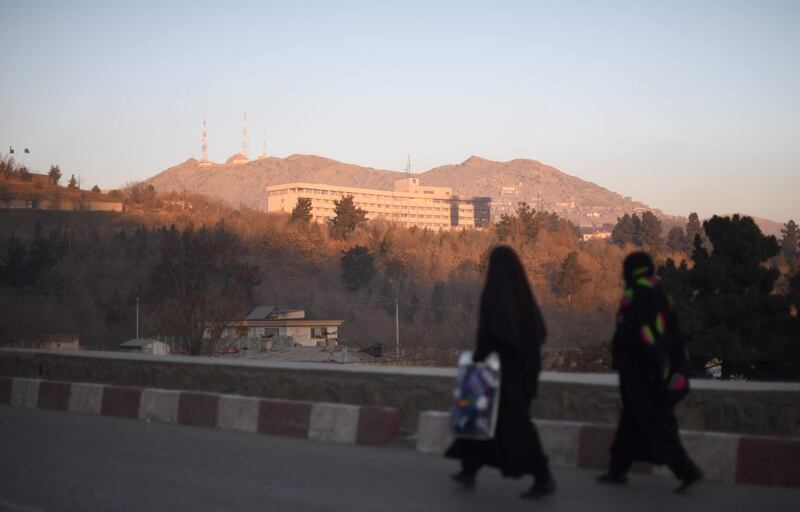 Two Afghan women walk past the Intercontinental Hotel after an attack in Kabul. Shah Marai / AFP Photo