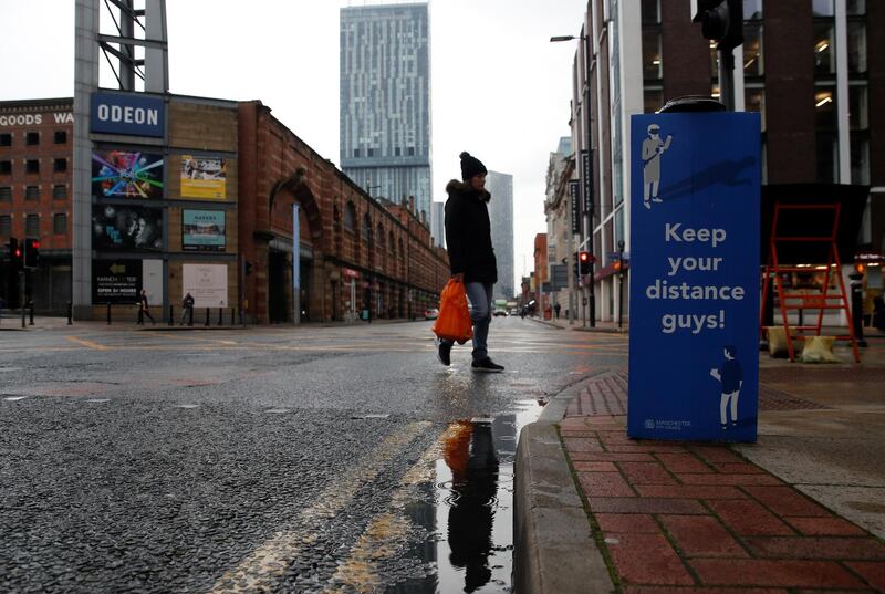 A woman walks near a social distancing sign in Manchester. Reuters