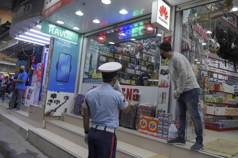 A Bahraini police officer instructs a foreign shop vendor to wear his protective mask amid the Covid-19 pandemic in the old market place of the Bahraini capital Manama. AFP