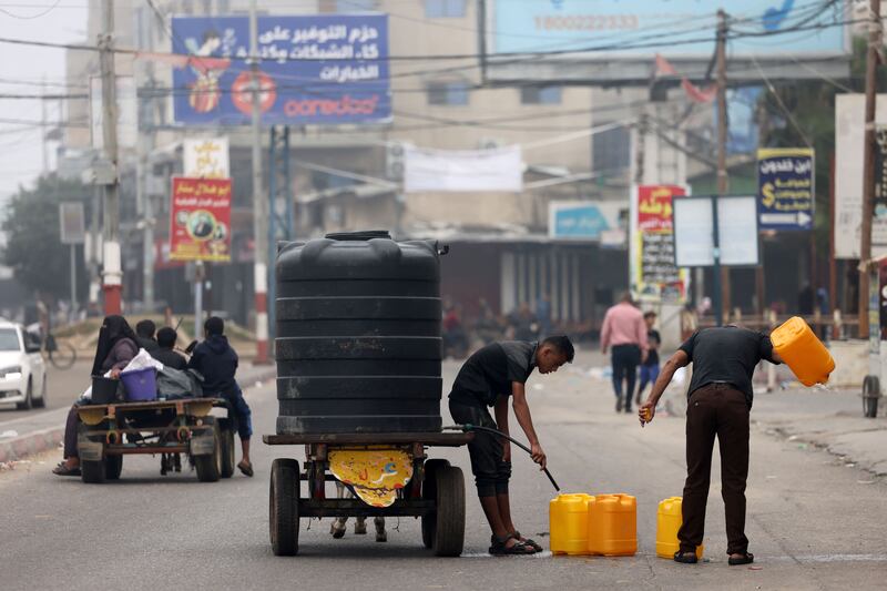 Men fill fuel containers with drinking water in Rafah. AFP