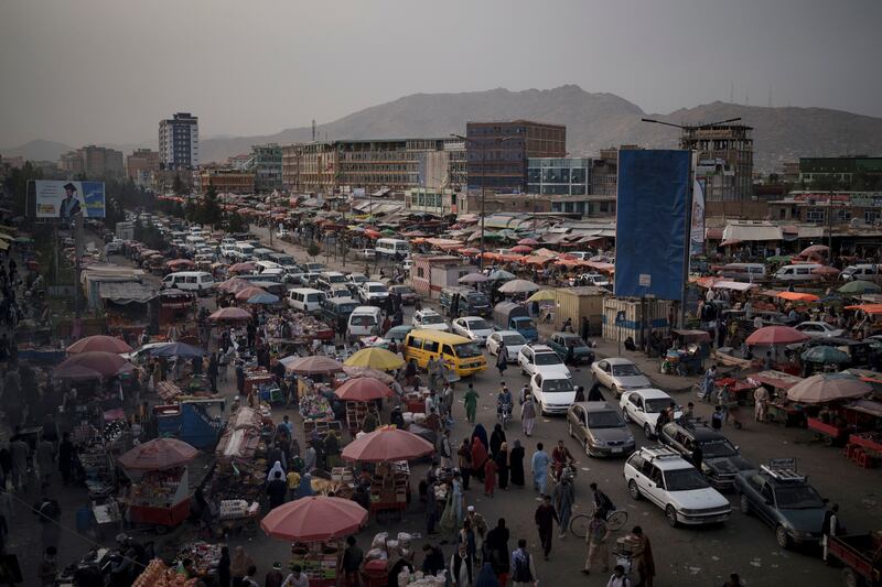 Cars wait in traffic as Afghans shop in a local market in Kabul. AP