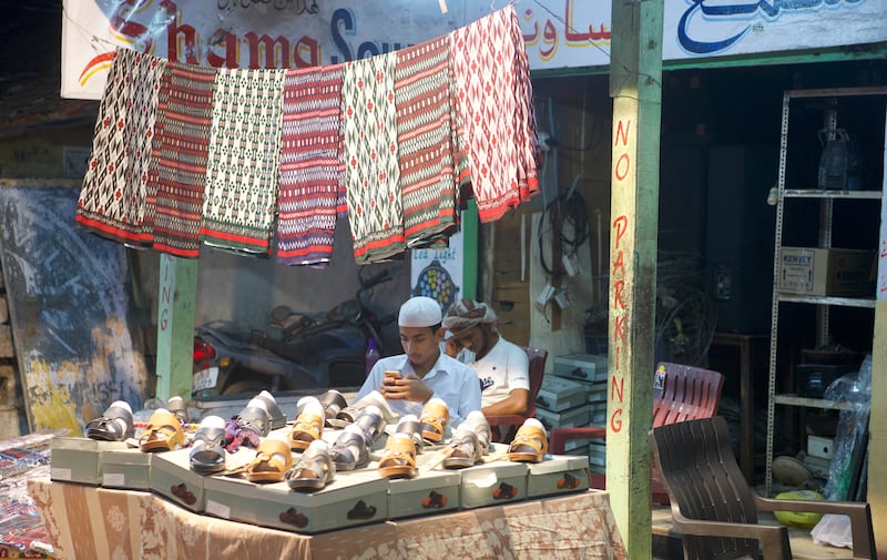 A shopkeeper sells futahs, traditional Yemeni menswear, and slippers in Barkas