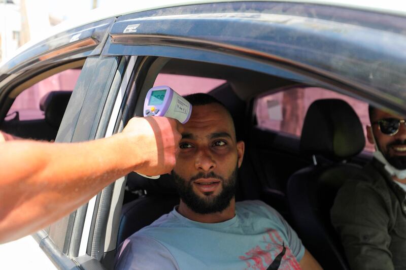 A Palestinian volunteer checks the temperature of a man entering the Amari refugee camp near the West Bank city of Ramallah.  AFP