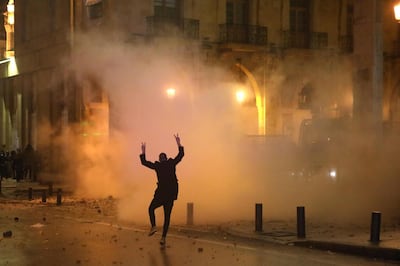 TOPSHOT - A Lebanese protester gestures at riot police guarding a road leading to parliament in central Beirut on January 19, 2020 amid ongoing anti-government demonstrations.  / AFP / PATRICK BAZ
