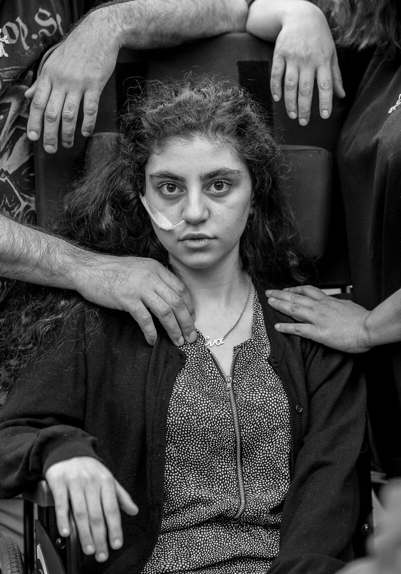 A photo by Tomek Kaczor shows Ewa, a 15-year-old Armenian girl who has recently woken from catatonic state brought on by  Resignation Syndrome, sits in a wheelchair, flanked by her parents, in a refugee reception center in Podkowa Leśna, Poland, on June 1, 2019. It won first prize in the Portraits category. Tomek Kaczor / EPA