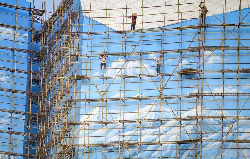 Workers are seen on a scaffolding outside a building in Haikou, Hainan province, China. Reuters