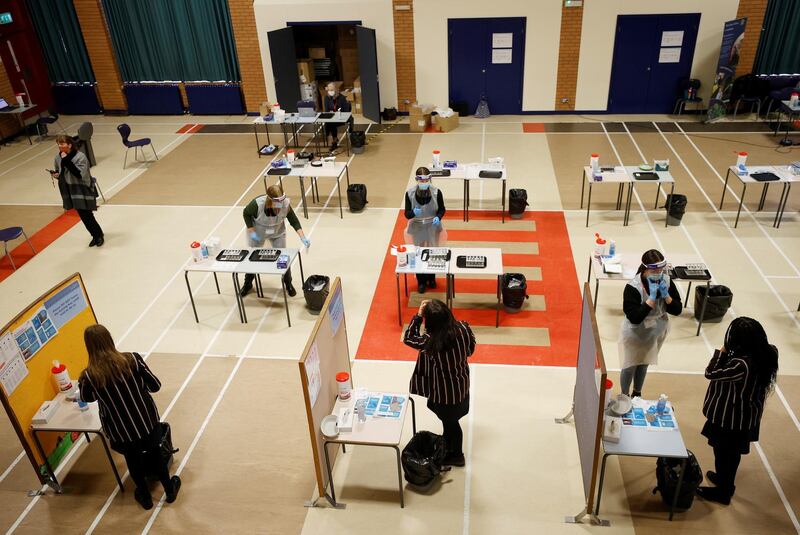 Students talk with volunteers before taking a coronavirus test in the school hall before returning to school at Loreto Grammar School in Altrincham. Reuters