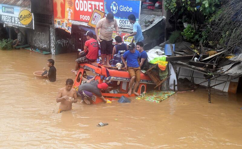 Residents are seen on top of a partially submerged vehicle along a flooded road in Cagayan de Oro city in the Philippines, on December 22, 2017. Froilan Gallardo / Reuters