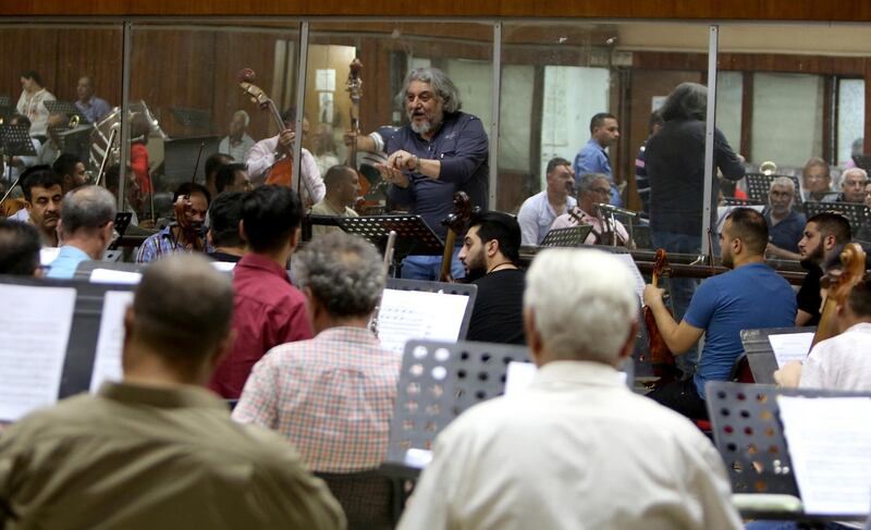 Iraqi National Symphony Orchestra conductor Mohammed Amin Ezzat leads musicians during a rehearsal on August 5, 2018 at Baghdad's School of Music and Ballet. - Some 40 musicians are gearing up to play at Baghdad's National Theatre on August 18, but the group's morale is at an all time low. The ensemble has lost more than half its members since the beginning of the year, when Baghdad introduced a directive barring state employees with two jobs from receiving two salaries. (Photo by SABAH ARAR / AFP)