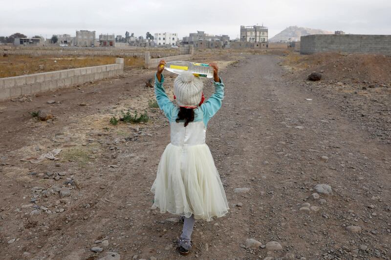 A Yemeni child carries a water bottle after filling it from a donated tank before going to school, on the outskirts of Sanaa. EPA