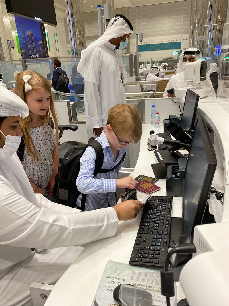 An immigration officer helps, Charles, 6, to stamp his passport at Dubai International Airport.