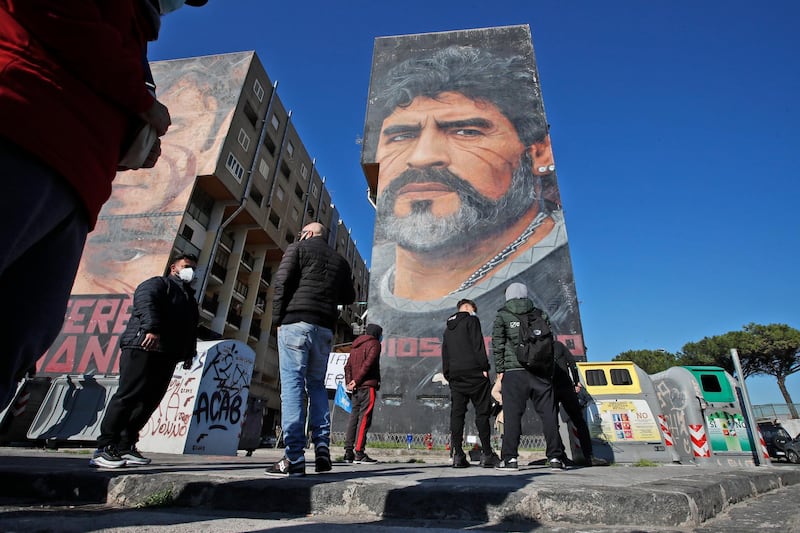 People gather beneath a giant mural of Diego Maradona in Naples. Reuters