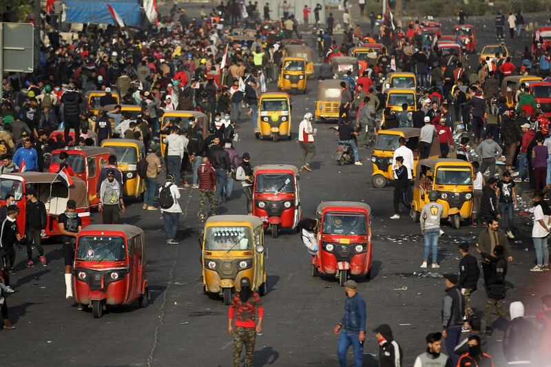 Iraqi protesters and Tuk-tuk drivers gather amid clashes with riot police following a demonstration at Baghdad's Tayaran Square, east of Tahrir Square.  AFP