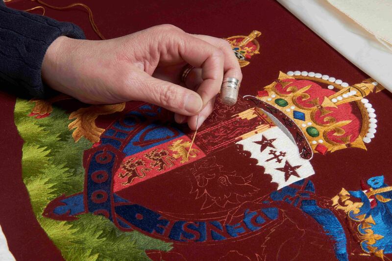 A member of the Royal School of Needlework works on the chair of state of Queen Consort Camilla before the coronation. PA