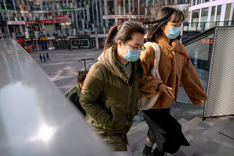 People wearing face masks to protect against the spread of the coronavirus walk at a shopping and office complex in Beijing. AP Photo