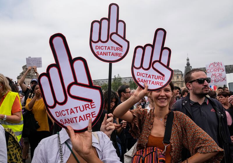 Protesters hold signs claiming that they are living in a health dictatorship, during a rally in Paris.