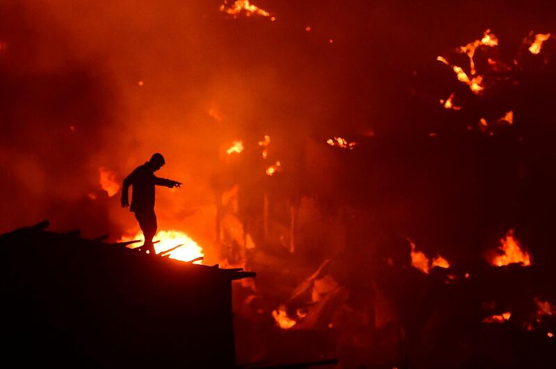 A Bangladeshi man tries to extinguish a fire as it blazes in a slum in Dhaka.  AFP