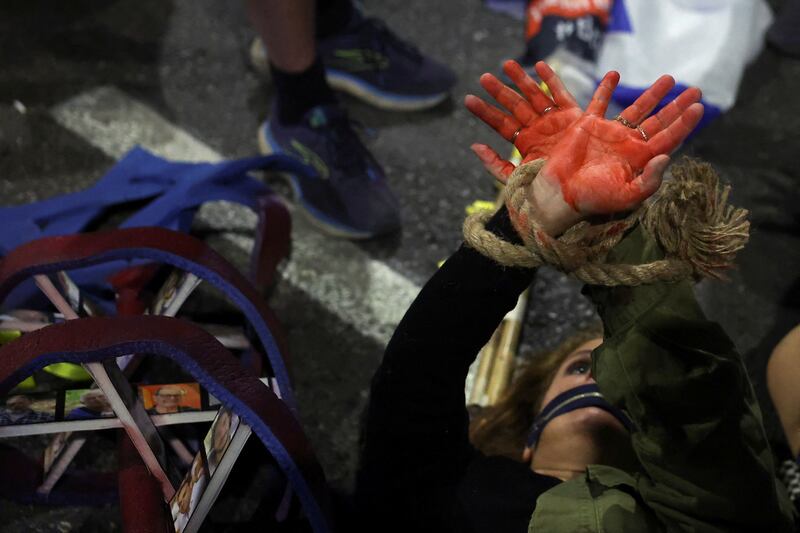 A demonstrator raises their hands with red paint while lying on the floor during a protest calling for the immediate release of hostages kidnapped in the October 7 attack. Reuters