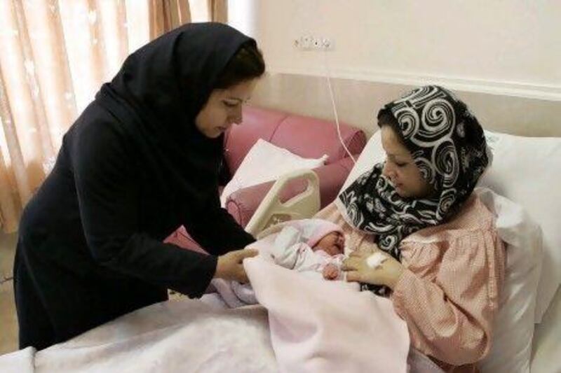 Iranian nurse Zahra Akbarzadeh (left) gives one-day-old girl Setayesh to her mother, Tayyebeh Sadat Bidaki, at the Mehr hospital, in Tehran. Iran is now slashing its birth control programmes.