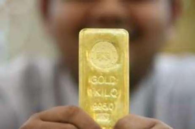 DUBAI, UNITED ARAB EMIRATES - DECEMBER 1:  Sachin Mahyavanshi holds up a one kilo gold bullion worth 98,000dhs (todayÕs price) at his store, Popley Jewellers, in the Gold Souk in Dubai on December 1, 2008.  (Randi Sokoloff / The National) 