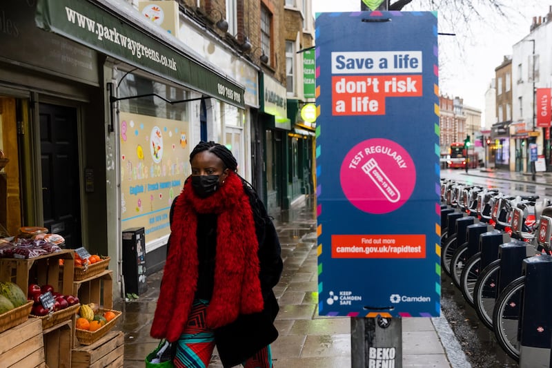 A woman walks past a Covid-19 testing sign in London. EPA