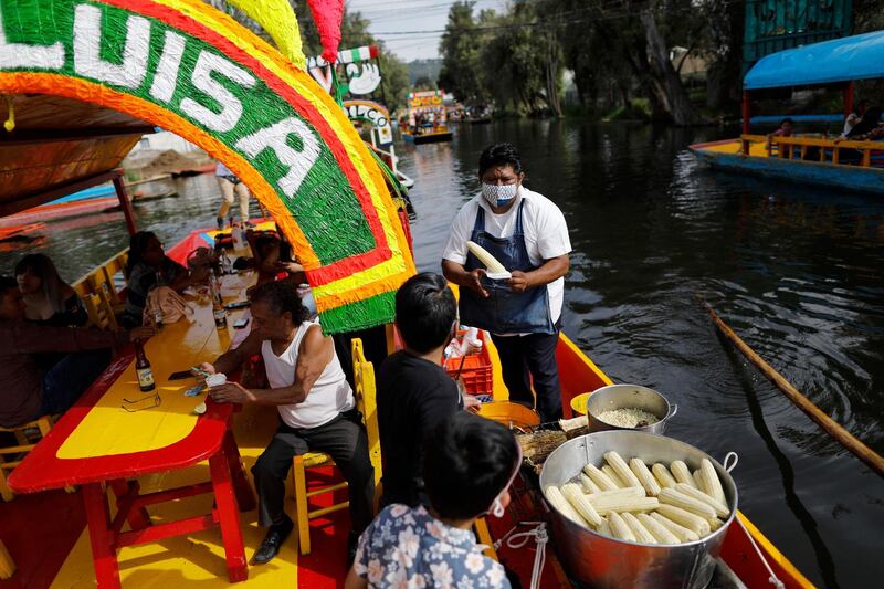 A vendor sells corn to a family aboard a trajinera, one of the painted wooden boats popular with tourists and revellers, after Xochimilco's docks reopened this weekend to tourists and revellers in Mexico City. AP Photo