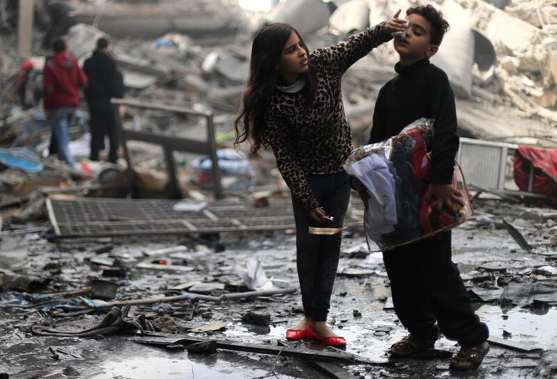 A Palestinian girl cleans the face of her brother outside their destroyed house. Reuters