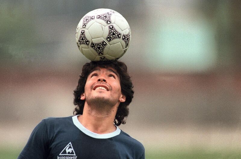 (FILES) In this file picture taken on May 22, 1986 Argentine football star Diego Maradona, wearing a diamond earring, balances a soccer ball on his head as he walks off the practice field following the national team's practice session in Mexico City. Argentine football legend Diego Maradona turns 60 on October 30, 2020.   / AFP / JORGE DURAN
