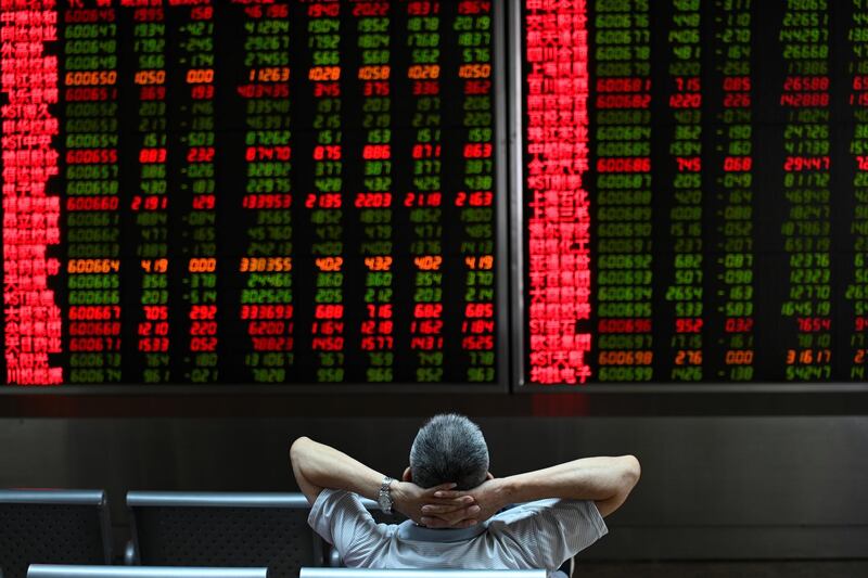 A Investor looks at screens showing stock market movements at a securities company in Beijing on August 26, 2019. - Asian equity markets tanked and the yuan hit an 11-year low Monday after US President Donald Trump ramped up his trade war with China by hiking tariffs on more than half-a-trillion dollars worth of imports. (Photo by WANG Zhao / AFP)