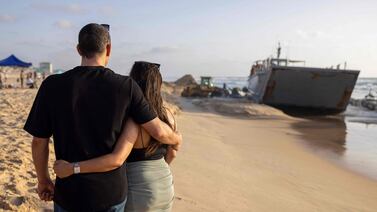 An Israeli couple look on as a digger attempts to extricate a US Army vessel that ran aground at a beach in Israel's coastal city of Ashdod. AFP