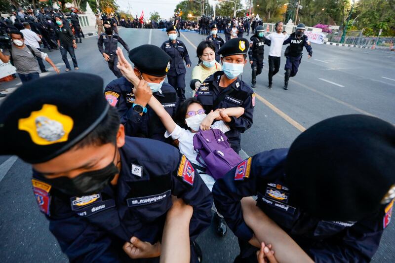 A pro-democracy protester flashes the three-finger salute while she is detained by police officers in front of the Government House during a rally in the Thai capital of Bangkok on March 28, 2021. Reuters