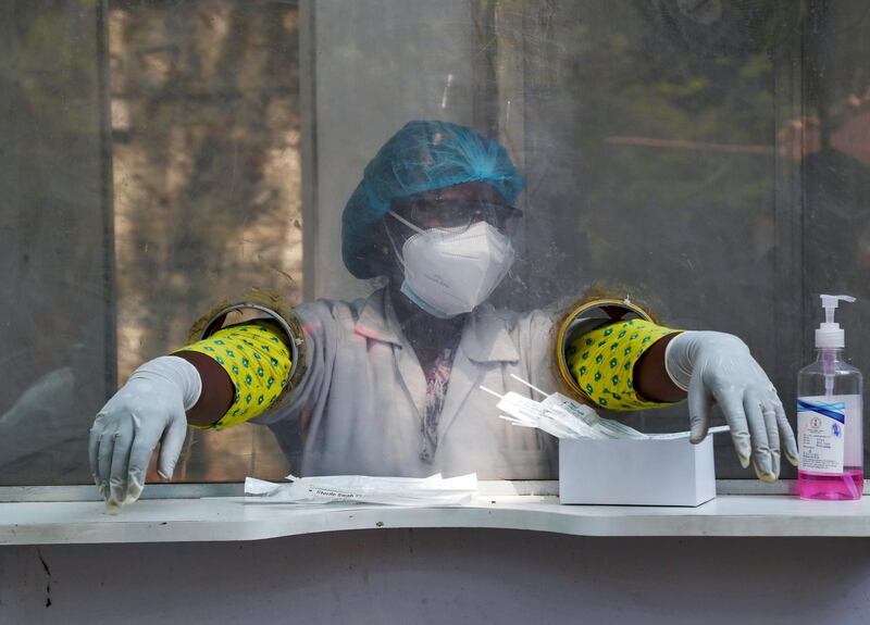 An Indian health worker takes a break while waiting to collect swab samples for Covid-19 tests in Hyderabad, India. AP Photo