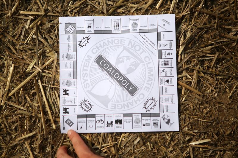 A climate change protester holds a mock version of monopoly handed out at the camp ahead of a walk on the grounds of open-pit coal mines in the Rhineland west of Cologne. Omer Messinger / Getty Images