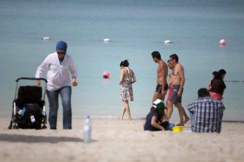 People enjoy the public beach on Abu Dhabi's Corniche. Many women say they still feel uncomfortable on mixed beaches and are calling for the reinstatement of segregated areas.