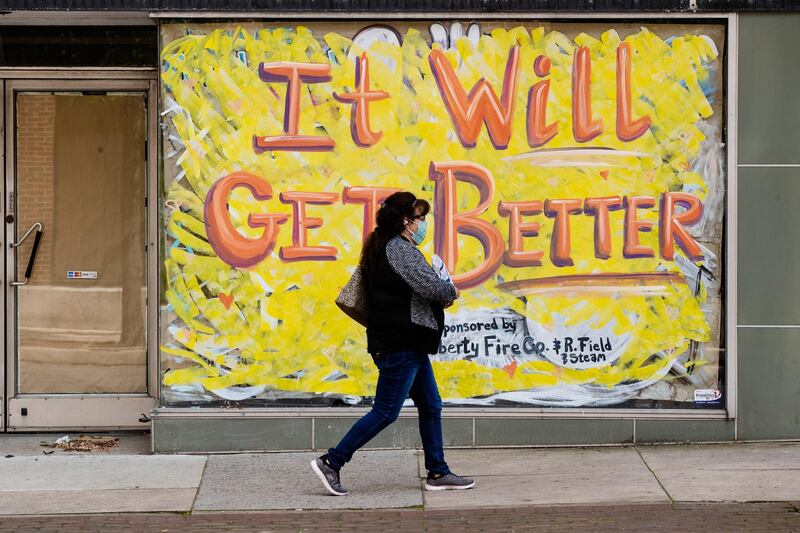 A person wearing a protective face mask as a precaution against the coronavirus walks by a closed storefront in Lebanon, Pennsylvania.  AP Photo