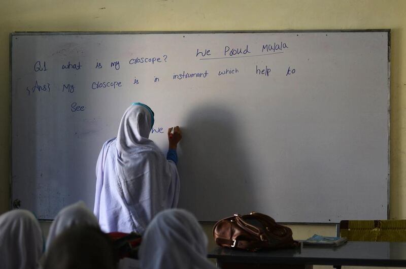 A Pakistani schoolgirl writes on a blackboard during class after offering prayers for Nobel Peace Prize laureate Malala Yousafzai during a school assembly in Mingora in the Swat valley on December 10, 2014. A Majeed / AFP 