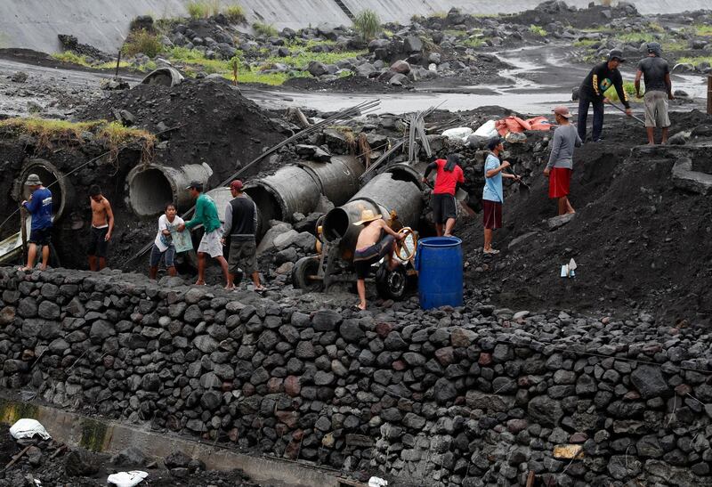 Filipino villagers work during a downpour at a flood control facility at the slope of the rumbling Mayon Volcano in Legaspi City, Albay province, Philippines. Francis Malasig / EPA