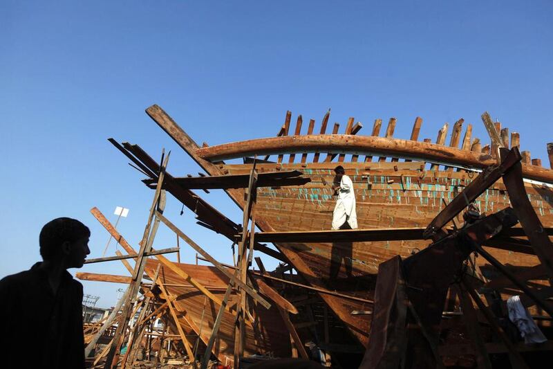 A worker is silhouetted as a carpenter works on a boat at a yard in Karachi's Fish Harbour. Akhtar Soomro / Reuters