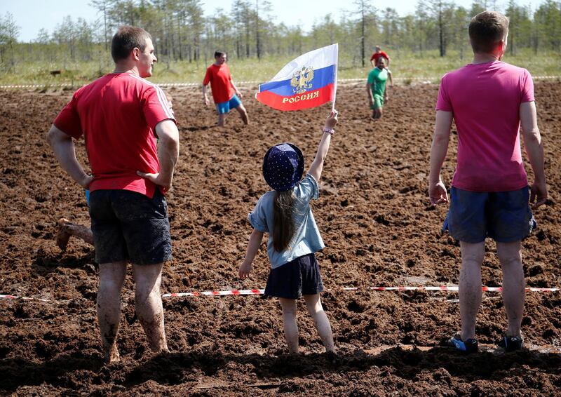 A girl holds a flag as she attends the Swamp Football Cup of Russia in the village of Pogi in Leningrad Region, Russia June 16, 2018. Anton Vaganov / Reuters