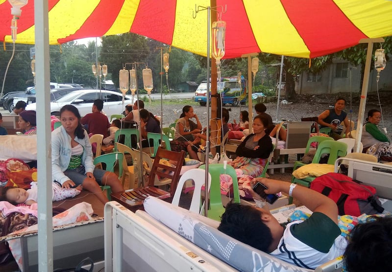Patients and residents rest outside a hospital in Makilala town, North Cotabato province in southern island of Mindanao on October 17, 2019, after a 6.3 magnitude earthquake hit the island.  A child was killed in a strong 6.4-magnitude quake that hit the southern Philippines on Wednesday, a local mayor said, as houses collapsed, power was knocked out and a shopping mall burst into flames. / AFP / Geonarri SOLMENARO

