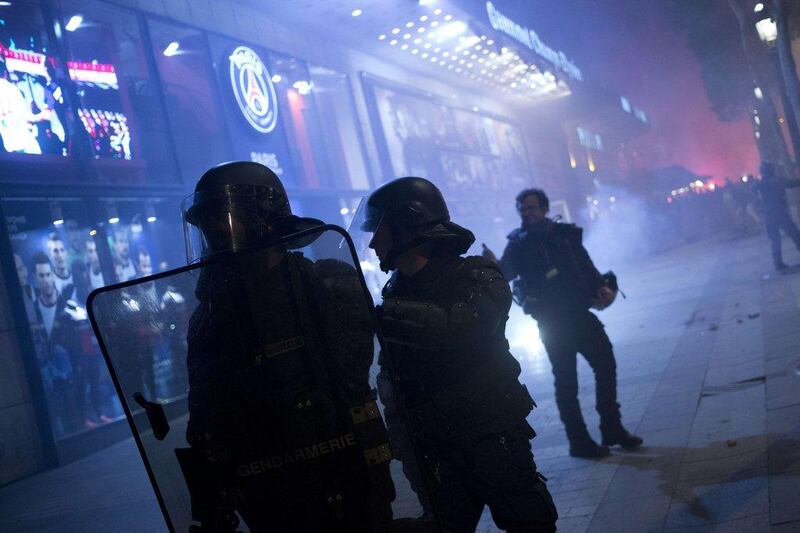 French gendarmes stand guard in front of the PSG shop on Wednesday during Ligue 1 title celebrations around Paris. Kenzo Tribouillard / AFP / May 7, 2014