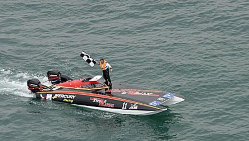 Salem Fadel al Hamli waves a victory flag after Extreme Marine's win in the XCat Middle East Championships race in Dubai yesterday.