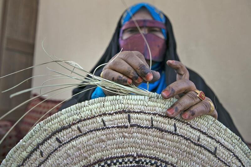 Madyah al Rameethy weaves a traditional palm-leaf place mat. Silvia Razgova / The National