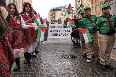 Palestinian youth members of the scouting movement hold up banners condemning and calling for an end of the conflict in Bethlehem in the occupied West Bank, on December 24. AFP