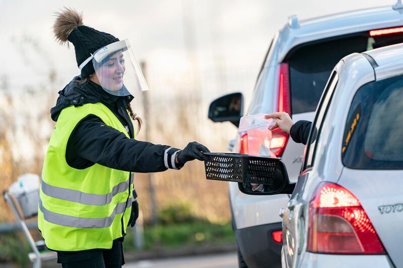 A woman wearing a face shield is handed a Covid-19 self-test at a sampling site in a car park at Svagertorp station in Malmo, Sweden. AP Photo