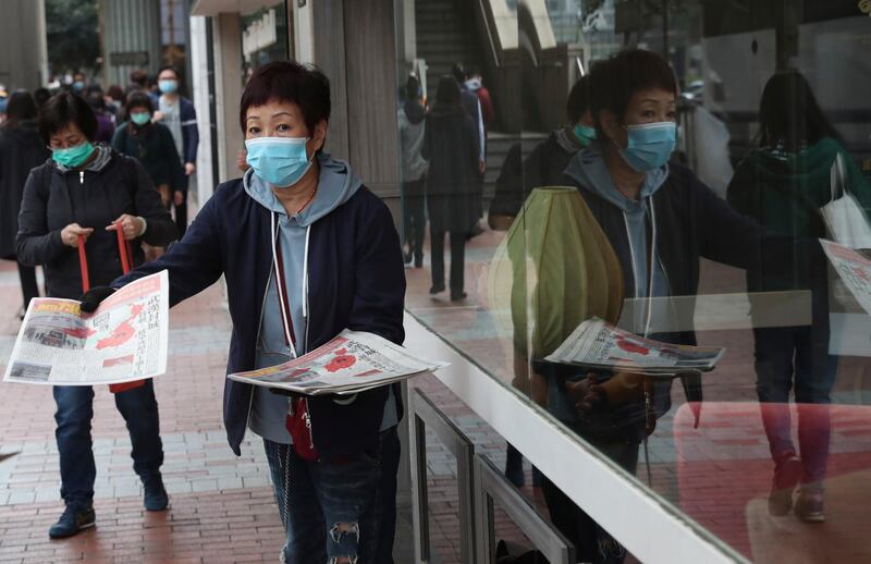 A woman wearing a protective face mask hands out leaflets on the coronavirus in Hong Kong. AP Photo