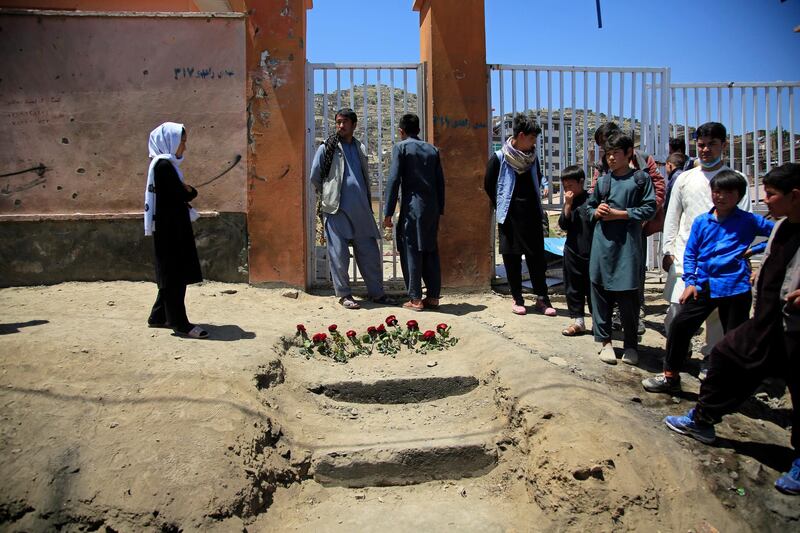 People puts flowers outside a school after a deadly attack on Saturday, in Kabul, Afghanistan, Sunday, May 9, 2021. The Interior Ministry said Sunday that the death toll in the horrific bombing at the entrance to the girls' school in the Afghan capital has soared to some 50 people, many of them pupils between 11 and 15 years old, and the number of wounded in Saturday's attack has also climbed to more than 100. (AP Photo/Mariam Zuhaib)