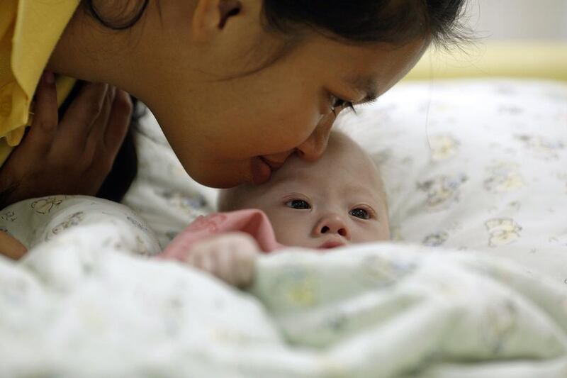 Gammy, a baby born with Down’s Syndrome, is kissed by his surrogate mother Pattaramon Chanbua. Reuters / August 3, 2014. 