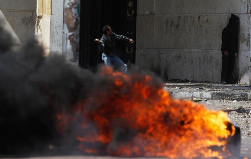 A protester, opposing Egyptian President Mohamed Mursi, throws a stone at riot police, near a fire, during clashes in front of Security Directorate in Port Said city, 170 km (105 miles) northeast of Cairo March 5, 2013. Police shot into the air and fired tear gas during clashes with hundreds of protesters in Egypt's Port Said on Tuesday, the third day of violent protests in the port city, a Reuters witness said. REUTERS/Amr Abdallah Dalsh (EGYPT - Tags: POLITICS CIVIL UNREST TPX IMAGES OF THE DAY) *** Local Caption ***  AMR010_EGYPT-PROTES_0305_11.JPG